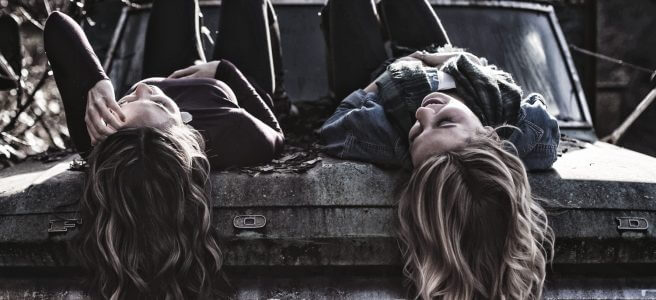 Sinnbildlich für Darmgesundheit liegen zwei junge Frauen entspannt auf der Motorhaube eines Pickups, plaudern und haben ihre Hände auf dem Bauch liegen.